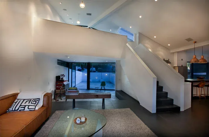 Modern living room with white walls, black tile floors, and a staircase with built-in storage area beneath.