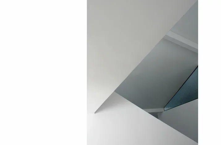 Interior architectural detail showing intersecting planes around a stairwell with a glass panel.