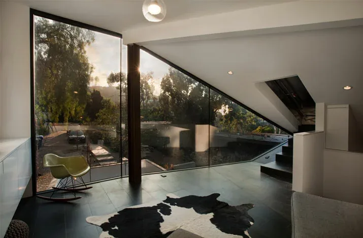 Living room interior with angled corner window and sloped ceiling providing natural light.