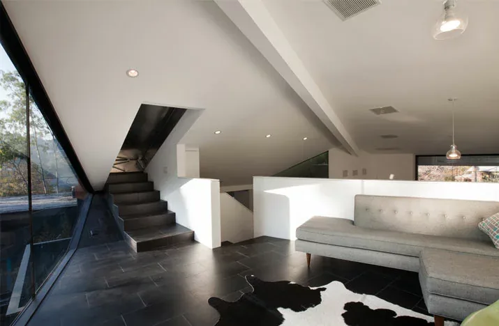 Living area features an angled ceiling and corner window providing natural light.