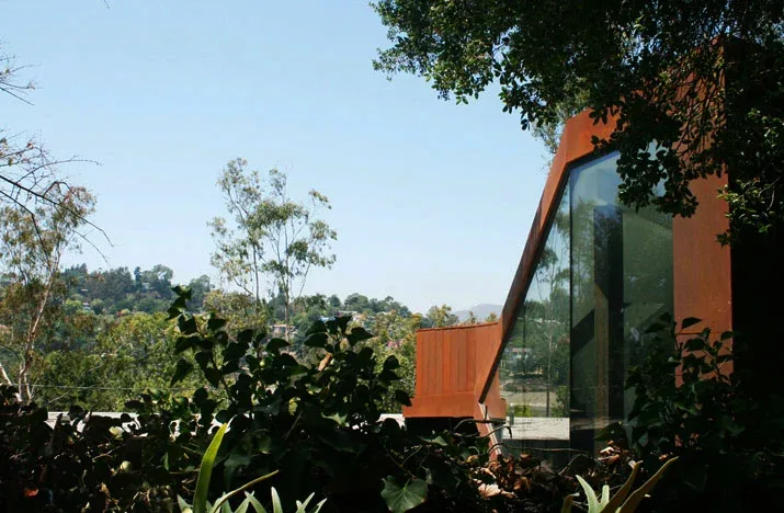 View of the Manifold House exterior featuring rusted steel cladding and large architectural glass window.