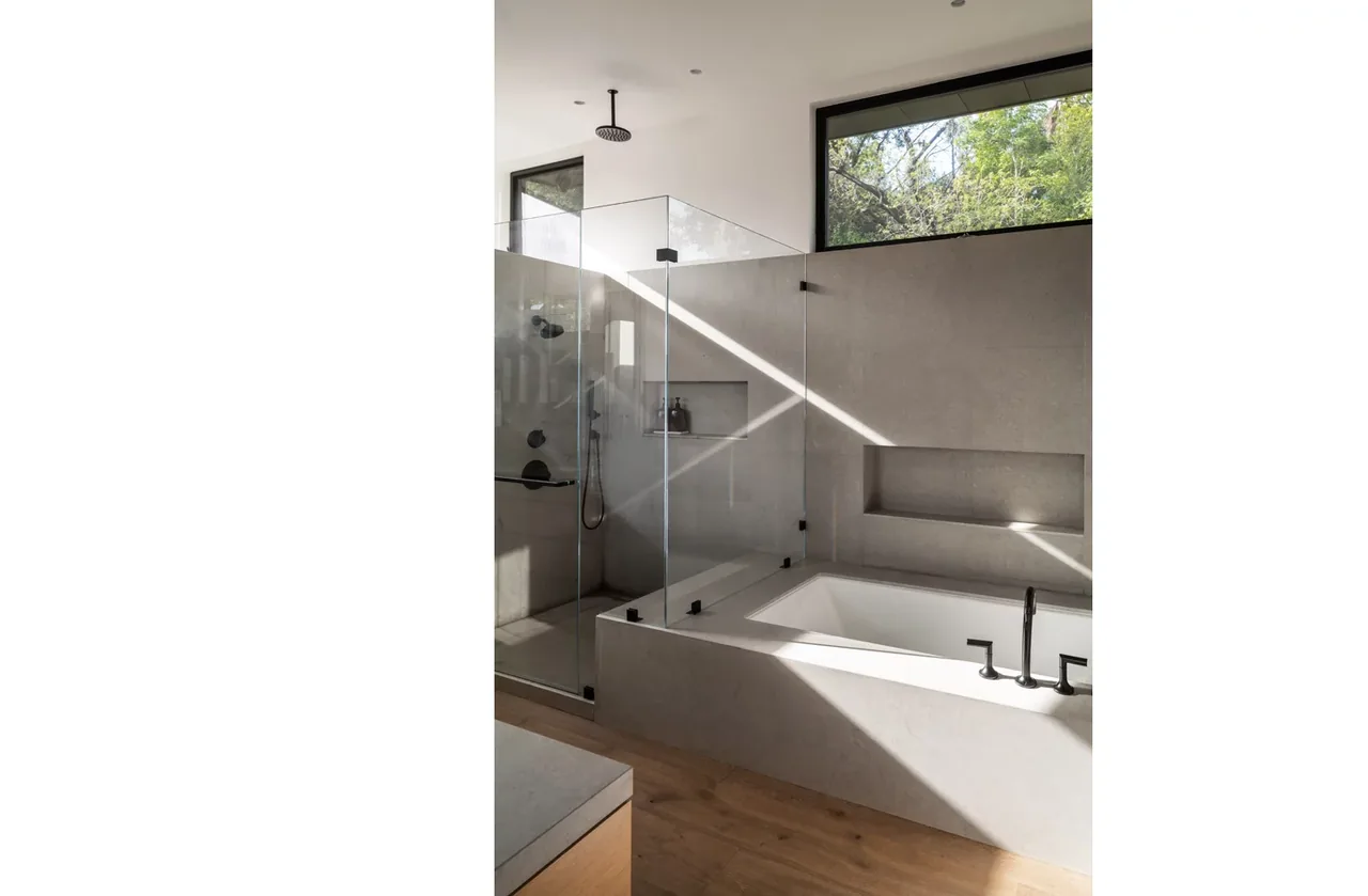 Bathroom with a walk-in shower with glass enclosure and a built-in bathtub next to it, illuminated by natural light from a horizontal window.