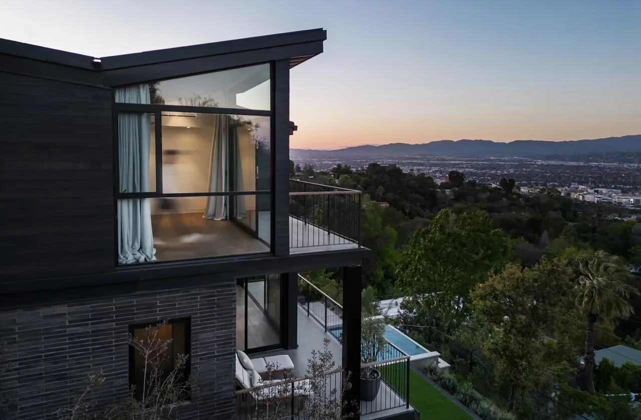 Modern two-story house featuring floor-to-ceiling glazing and balconies with city and mountain views.