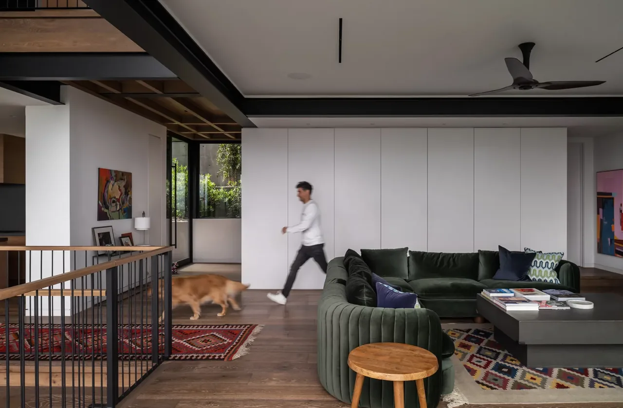Interior view of a modern living room with hardwood floors, a green sectional, and metal railing.