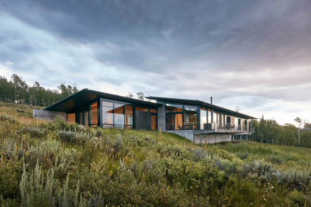 Wyoming Residence features a long horizontal facade with floor-to-ceiling glazing adapted to a sloping grassland site.