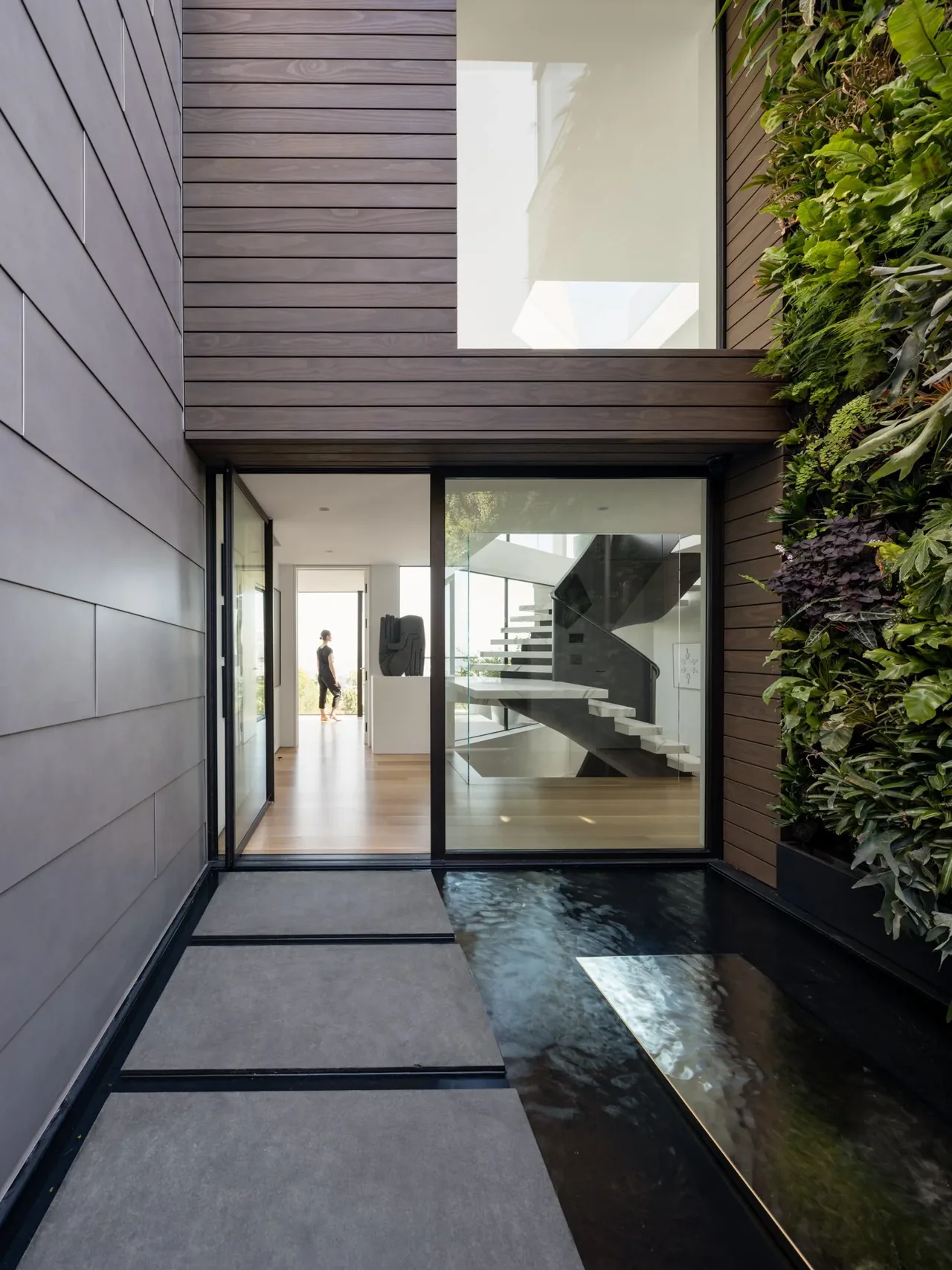 Entryway with water feature and vertical garden next to a glass sliding door leading to an interior staircase.