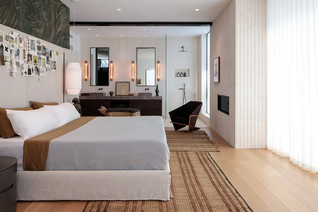 The primary bedroom features a bed, vanity area with mirrors, and an adjacent shower enclosed in glass.