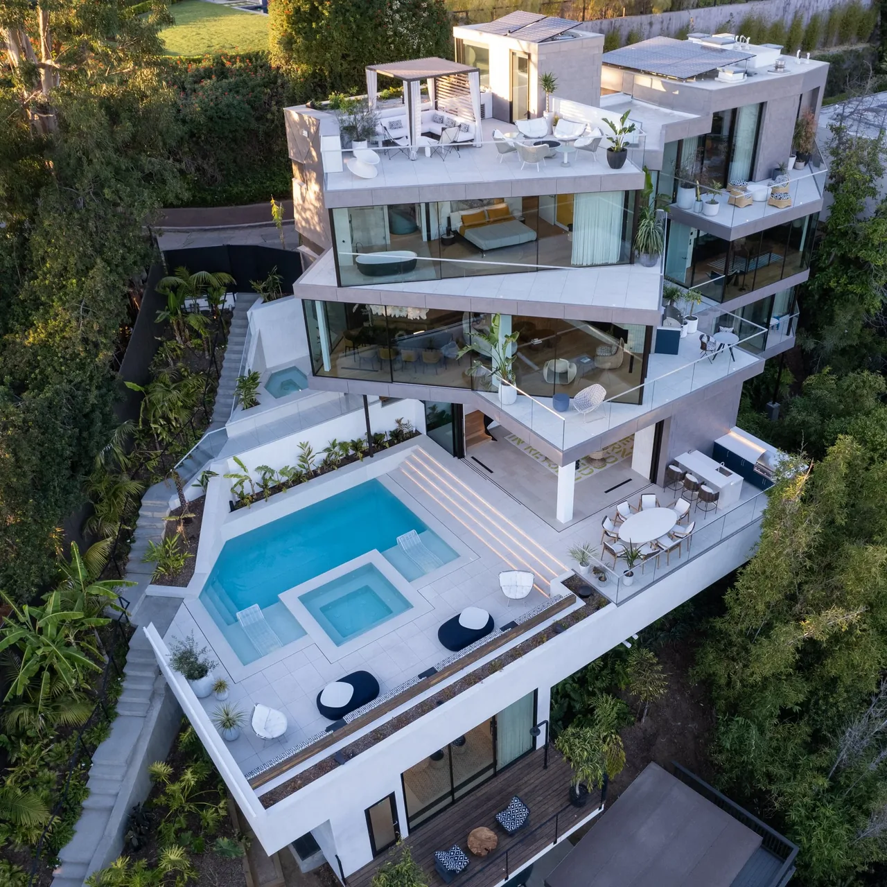 Aerial view of a multi-level contemporary residence featuring multiple outdoor terraces, a swimming pool, and a hot tub.