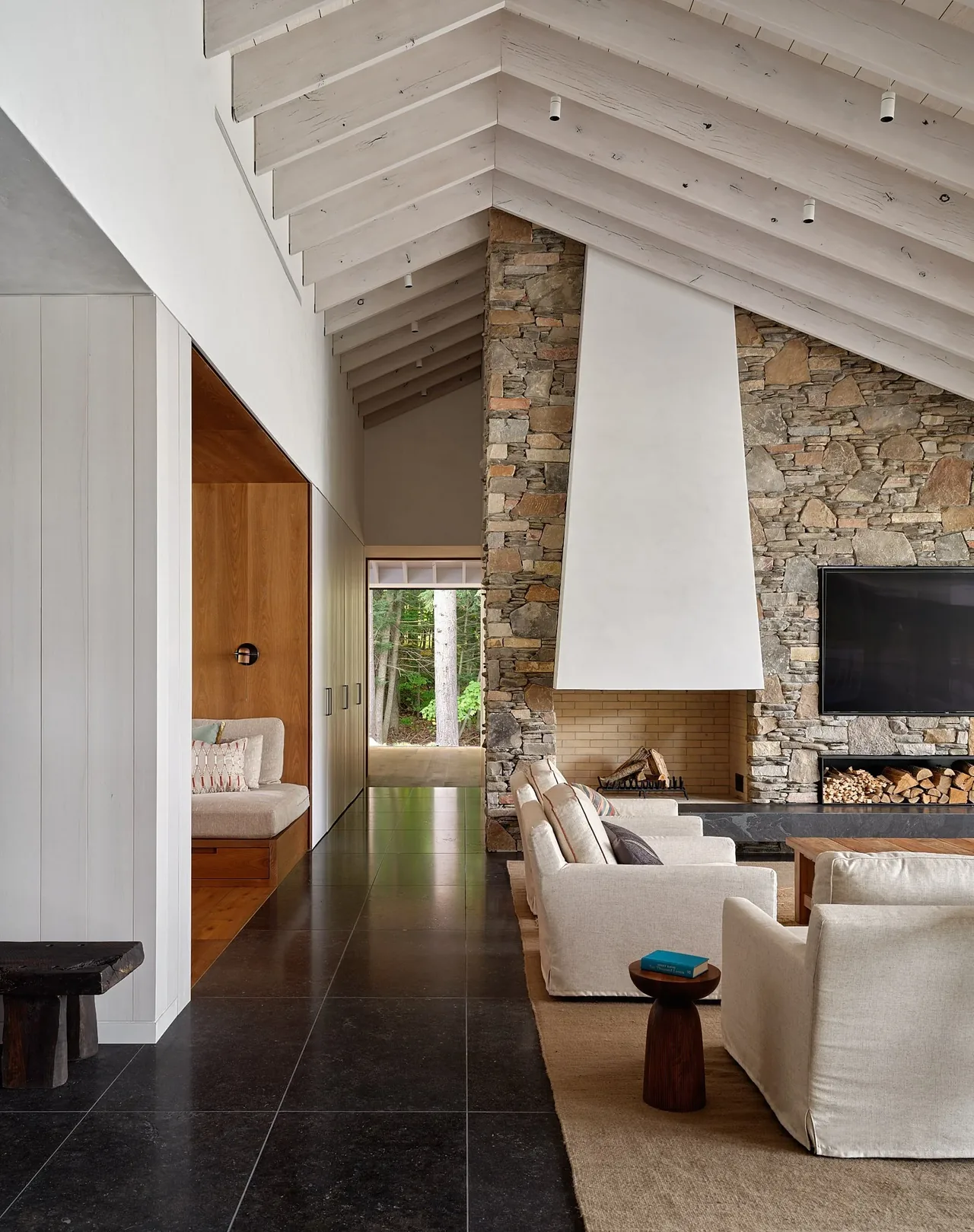 Interior view of a living room with a vaulted ceiling and a stone fireplace in the Muskoka Cottage project.
