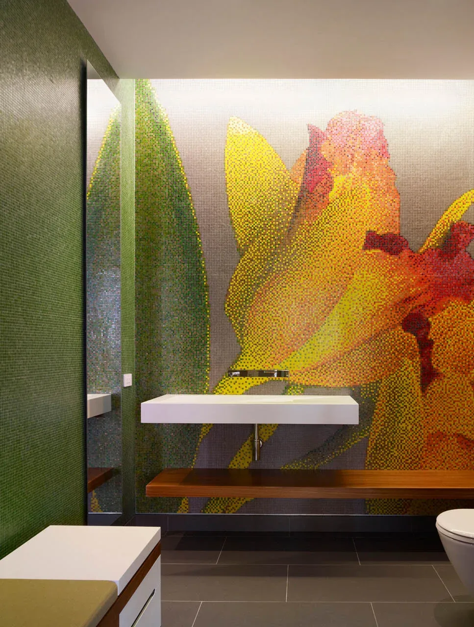 Powder room featuring a large floral mosaic tile wall and floating sink with wooden bench.