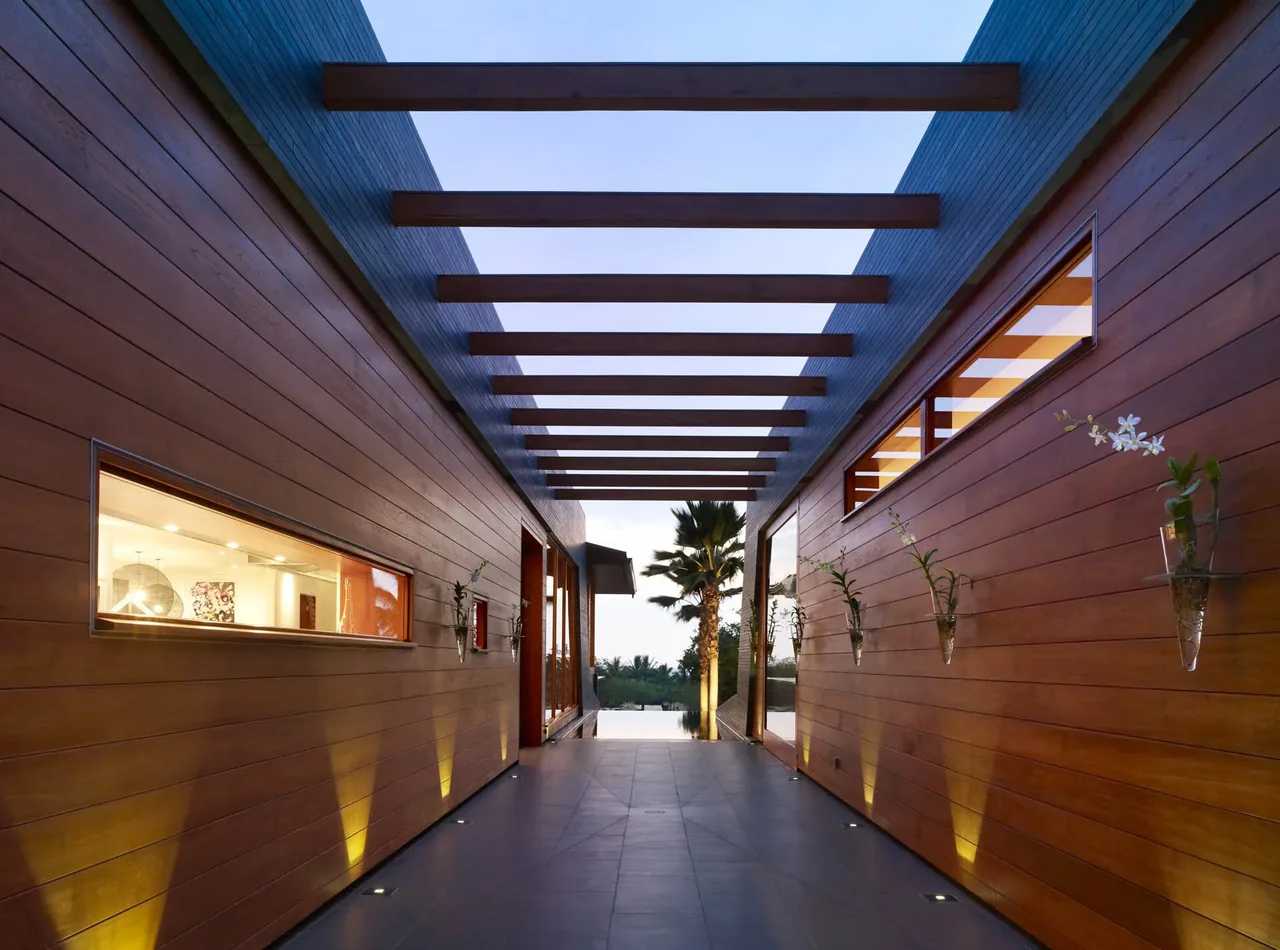 Exterior corridor with wood siding, recessed floor lights, exposed wooden overhead beams, and small rectangular windows.