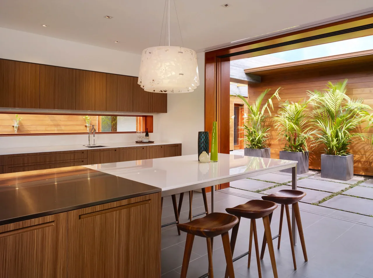Kitchen interior with wood cabinets and large island opening to outdoor patio through sliding glass doors.