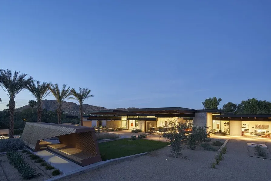 The Camelback Residence features modern design with a flat roof and large sliding glass doors opening to a desert landscape in Los Angeles.