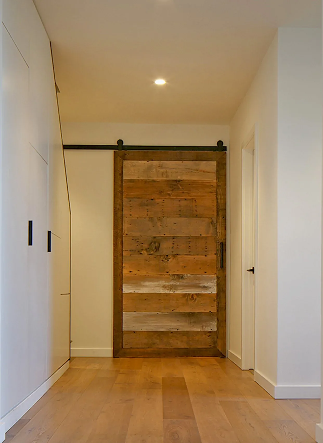 Hallway featuring a rustic wooden sliding barn door and light wood flooring.