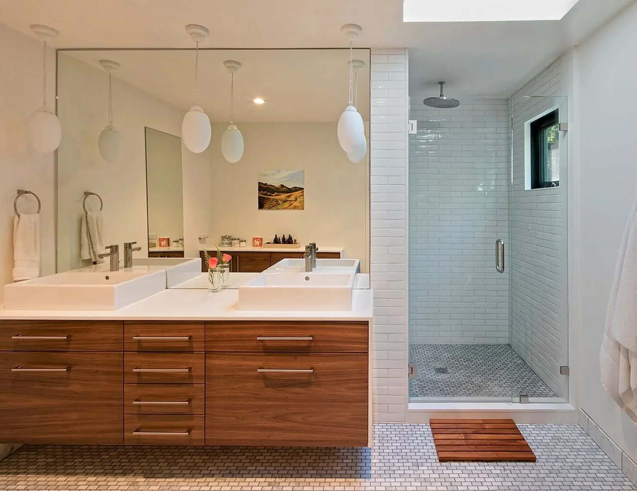 Bathroom features a floating wood vanity with vessel sinks and a walk-in shower with white subway tiles and a rainfall showerhead.