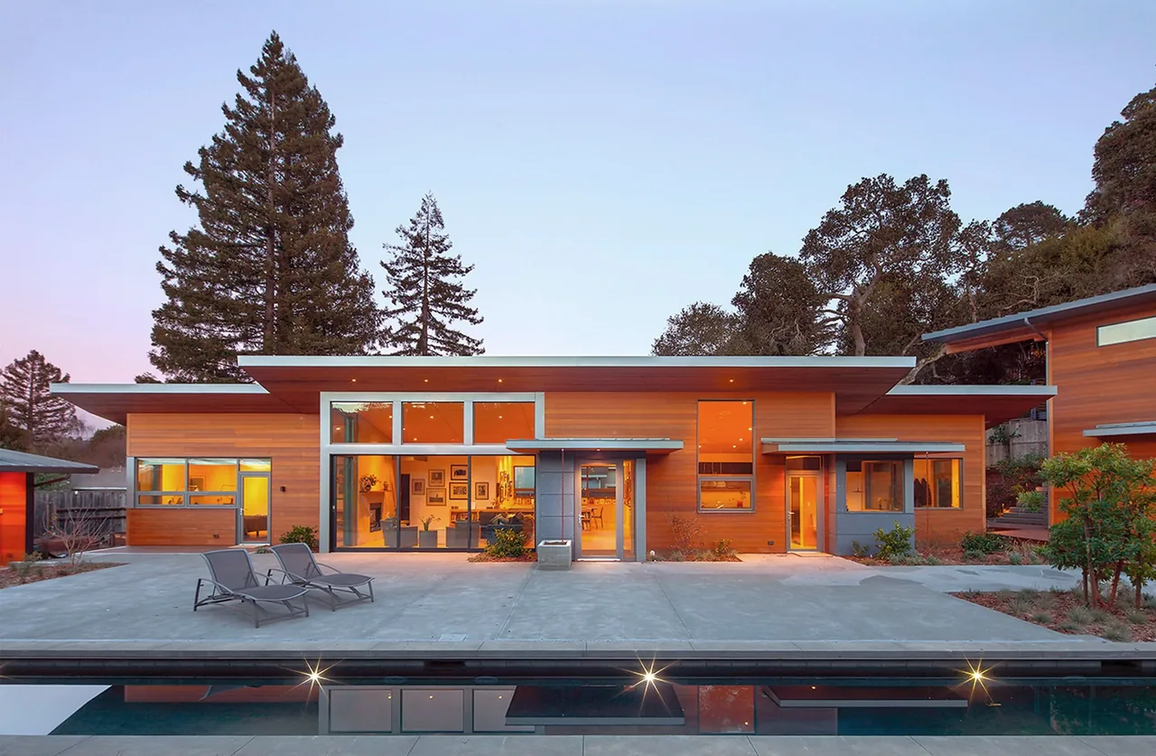 Net Zero Energy House by 361 Architecture features wood siding, floor-to-ceiling glazing, and a flat roof near a pool.