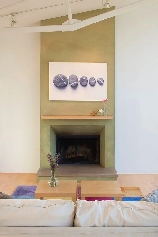 The living room features a fireplace with a green plaster surround and wooden mantel with simple floral decor.