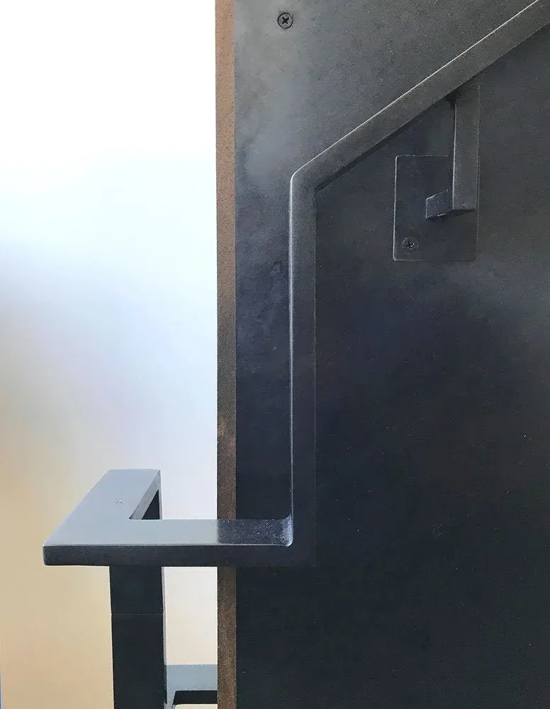Matte black metal handrail detail attached to wall showing angular geometry and finish.