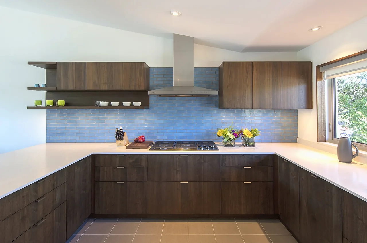 Kitchend with dark walnut cabinets, blue tile backsplash, and a stainless steel range hood above gas cooktop.