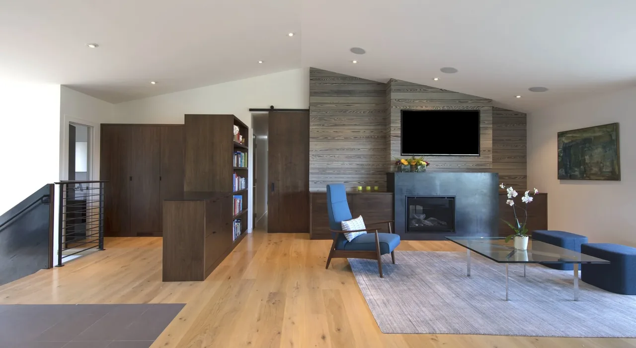 Living room features wood wall paneling, a fireplace, and a glass coffee table on a gray rug.
