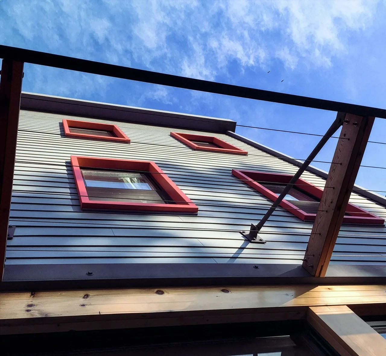 Brooklyn Townhouse exterior features horizontal siding with red window trim visible from below.