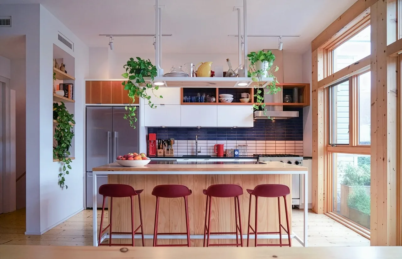Kitchen in Brooklyn Townhouse Renovation featuring wood island, hanging plants, and large window wall.