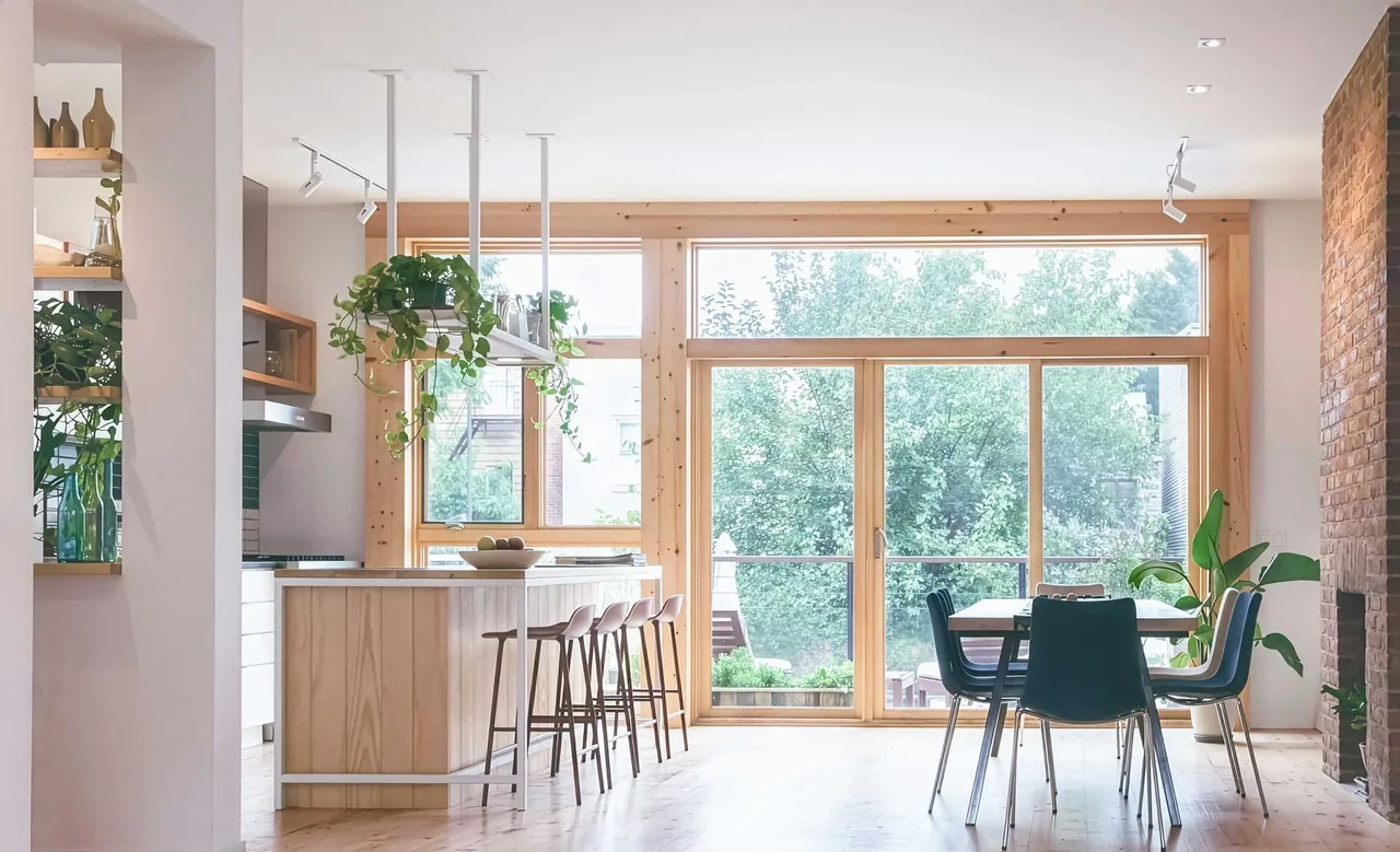 Bright open-plan kitchen and dining space features wood framing around large glass doors and an island with seating for four.