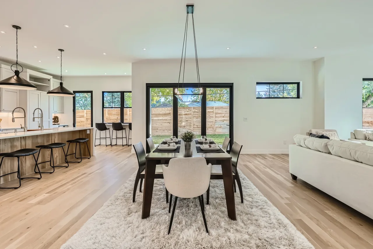Open plan dining and kitchen area with hardwood flooring and black-framed windows.
