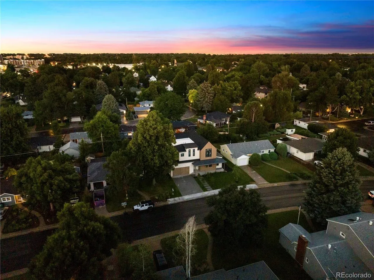 Aerial photo showing a two-story modern house amidst a suburban neighborhood at sunset.