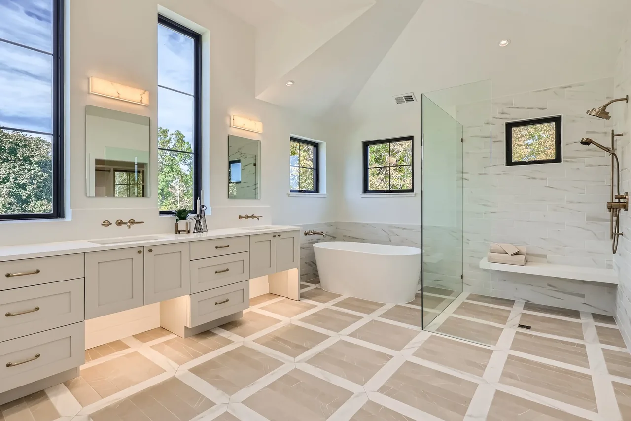 Modern bathroom featuring a floating dual-sink vanity, freestanding tub, and glass-enclosed shower with bench.