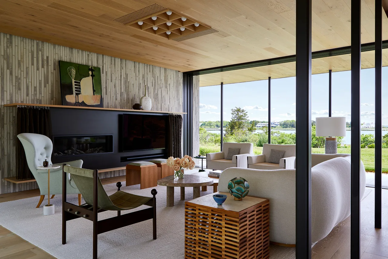 Living room with floor-to-ceiling glazing and a view of the outdoors at the Quogue Creek project by Bates Masi Architects.