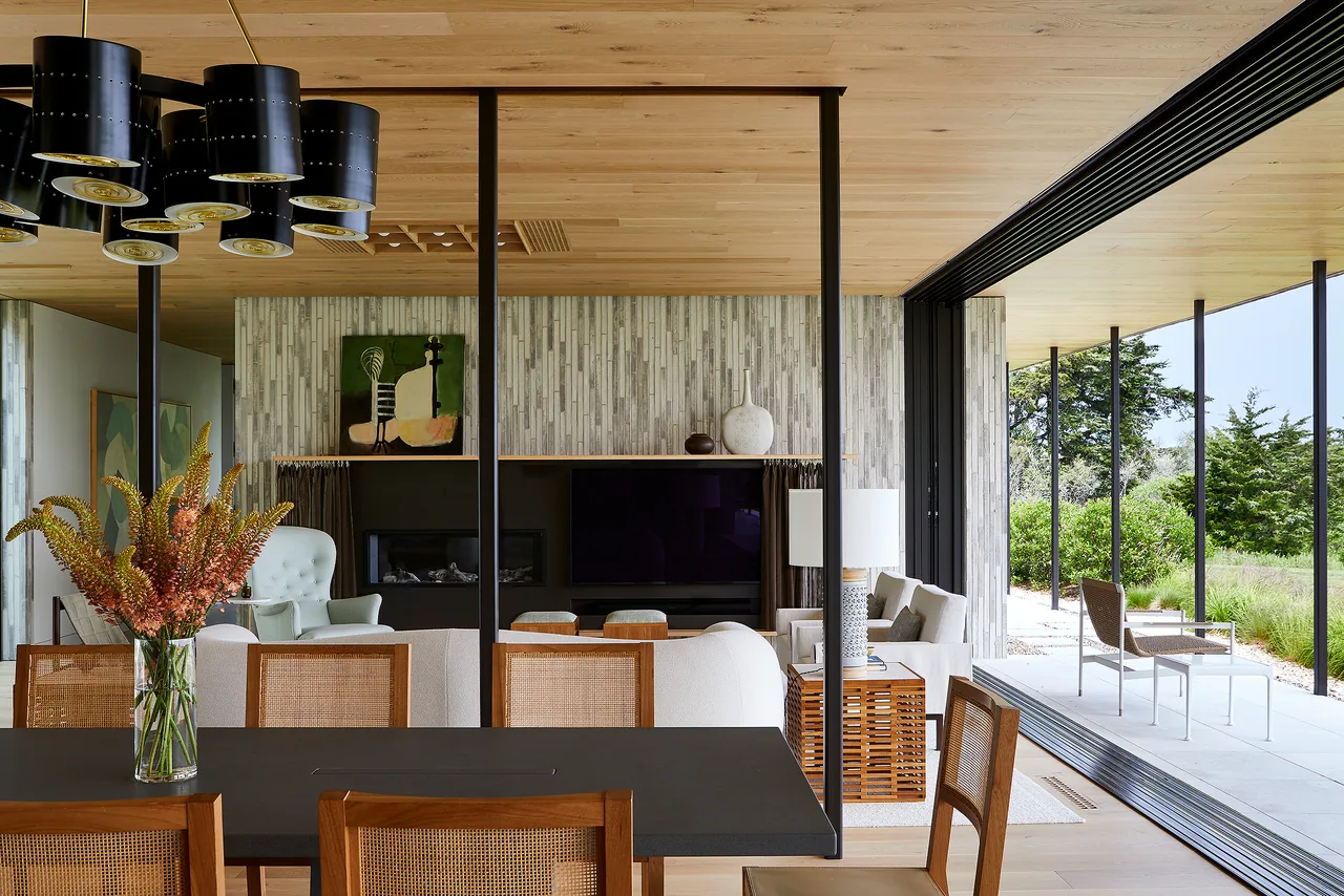 Interior view showing living and dining spaces with sliding glass doors opening to a patio surrounded by greenery.