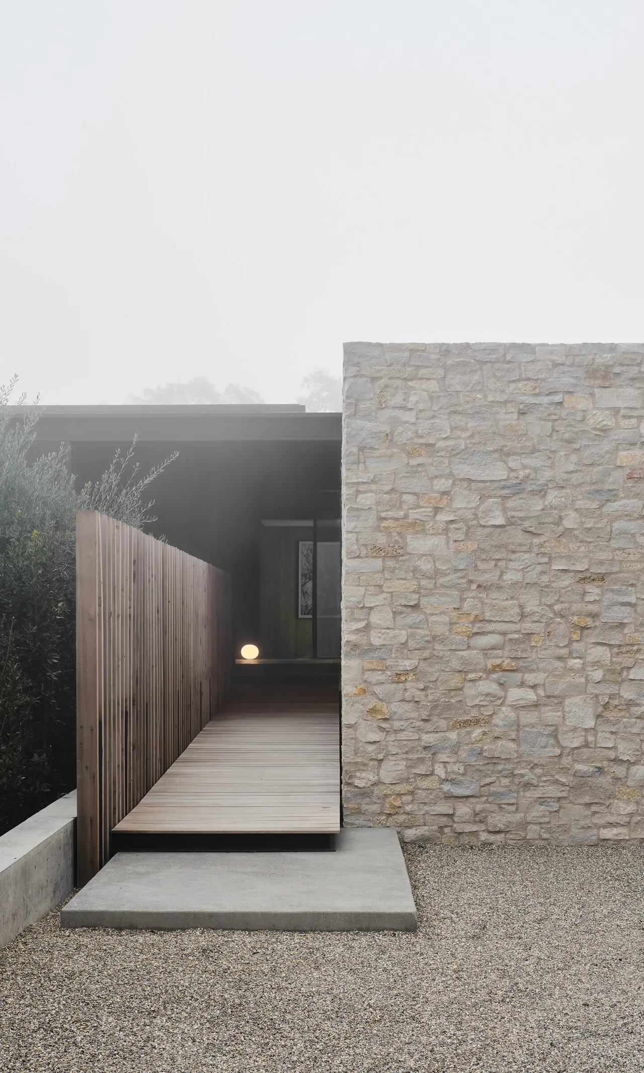 Wood-paneled entrance ramp and stone wall at the Trestle Residence by Aidlin Darling Design.