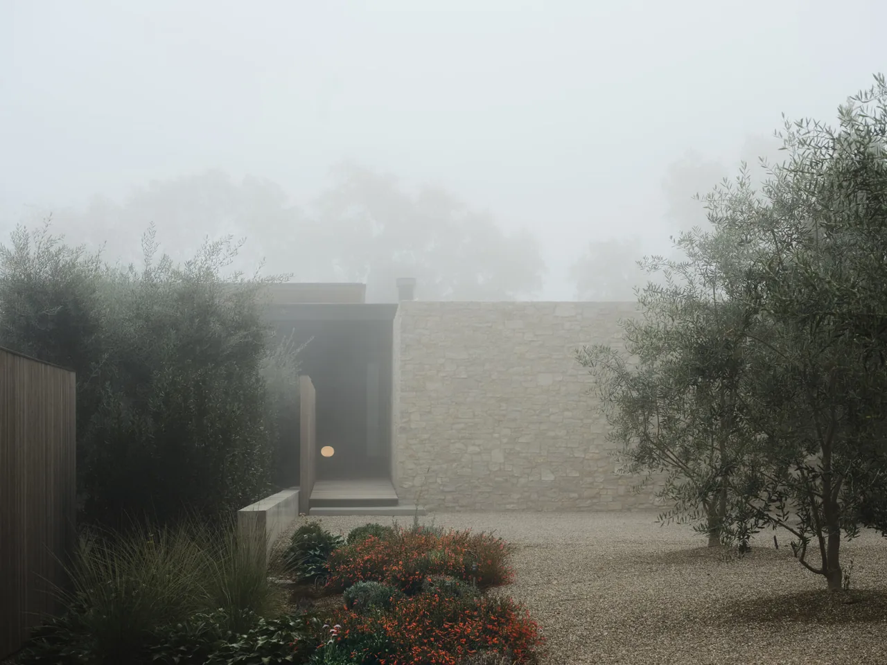 The Trestle Residence courtyard features a stone wall and lush plantings amid foggy conditions.