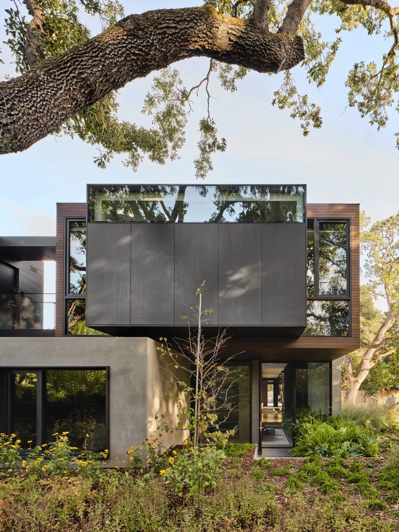 Modern residence featuring a cantilevered upper volume with floor-to-ceiling glazing over a concrete ground floor facade.