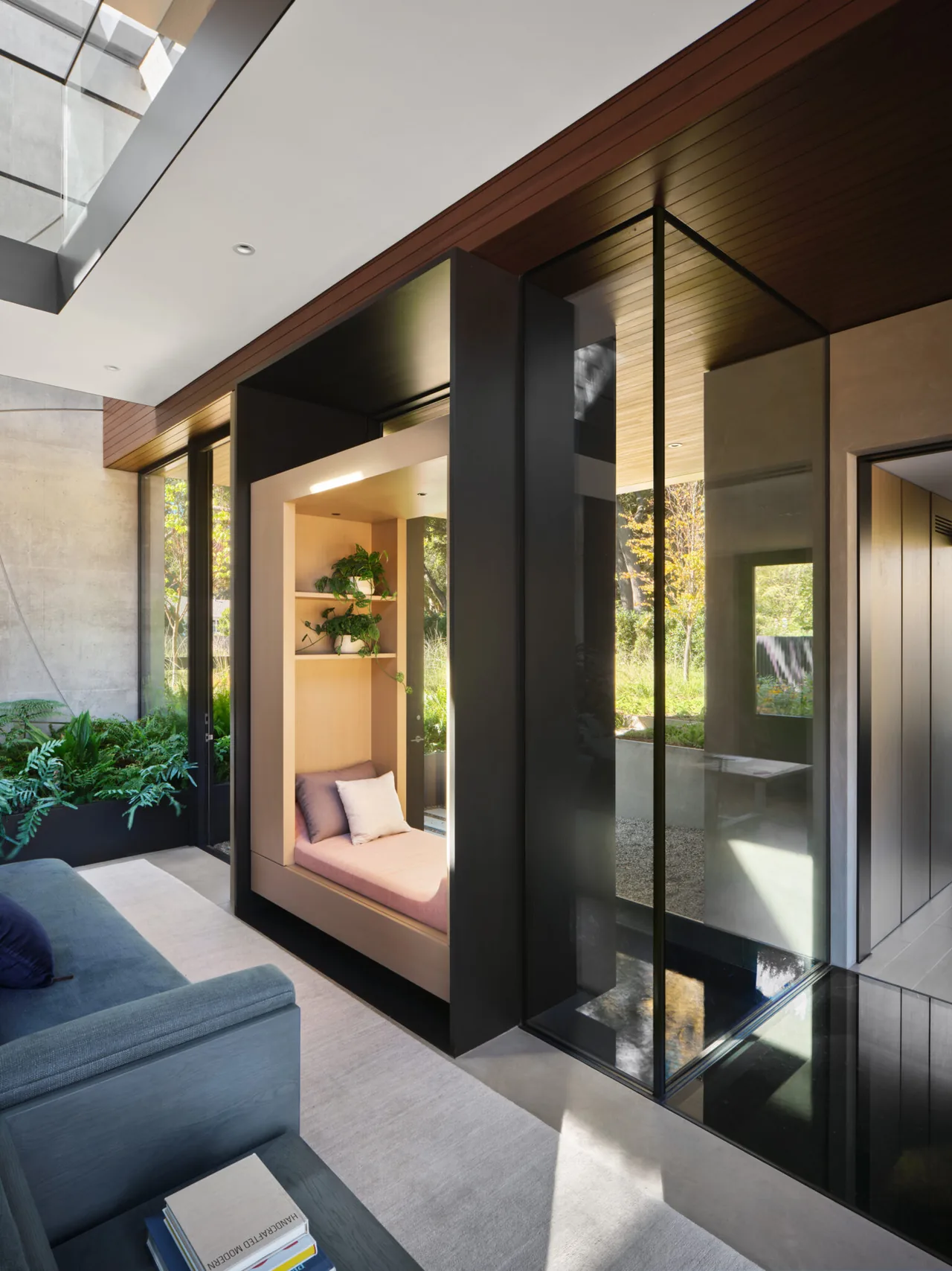 Interior view of a modern seating alcove integrated into a glass and wood wall assembly with natural light.