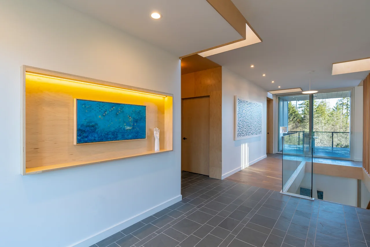 Hallway space with recessed display niche, wood and tile flooring, and a glass door leading to a balcony area.