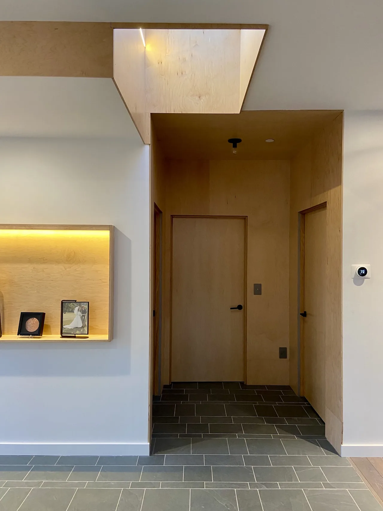 Hallway with wood panel doors, tiled flooring, and a skylight above.