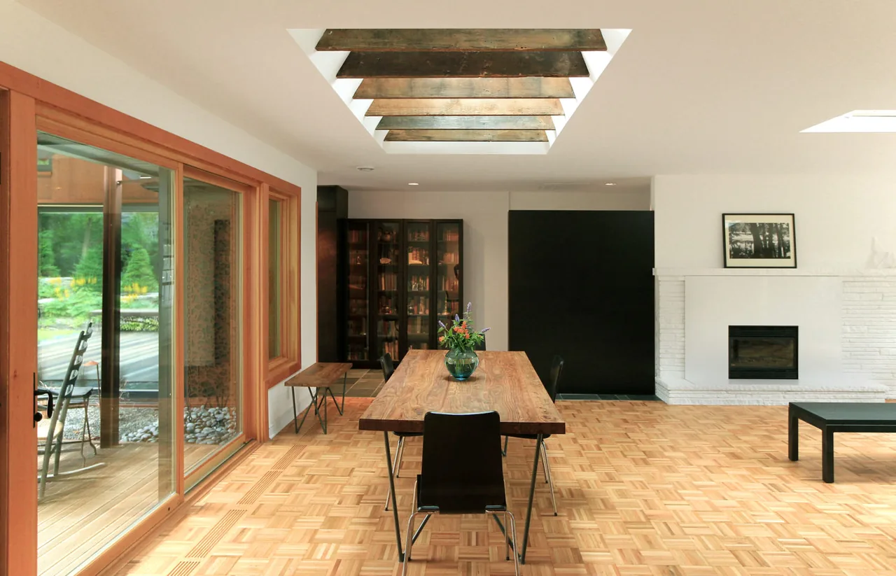 Dining space features a wooden table, parquet flooring, skylight with beams, and sliding glass doors to an outdoor area.
