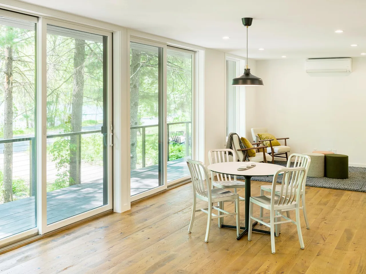 Lake Elmo weeHouse features a dining area with a round table and metal chairs beside floor-to-ceiling sliding glass doors.