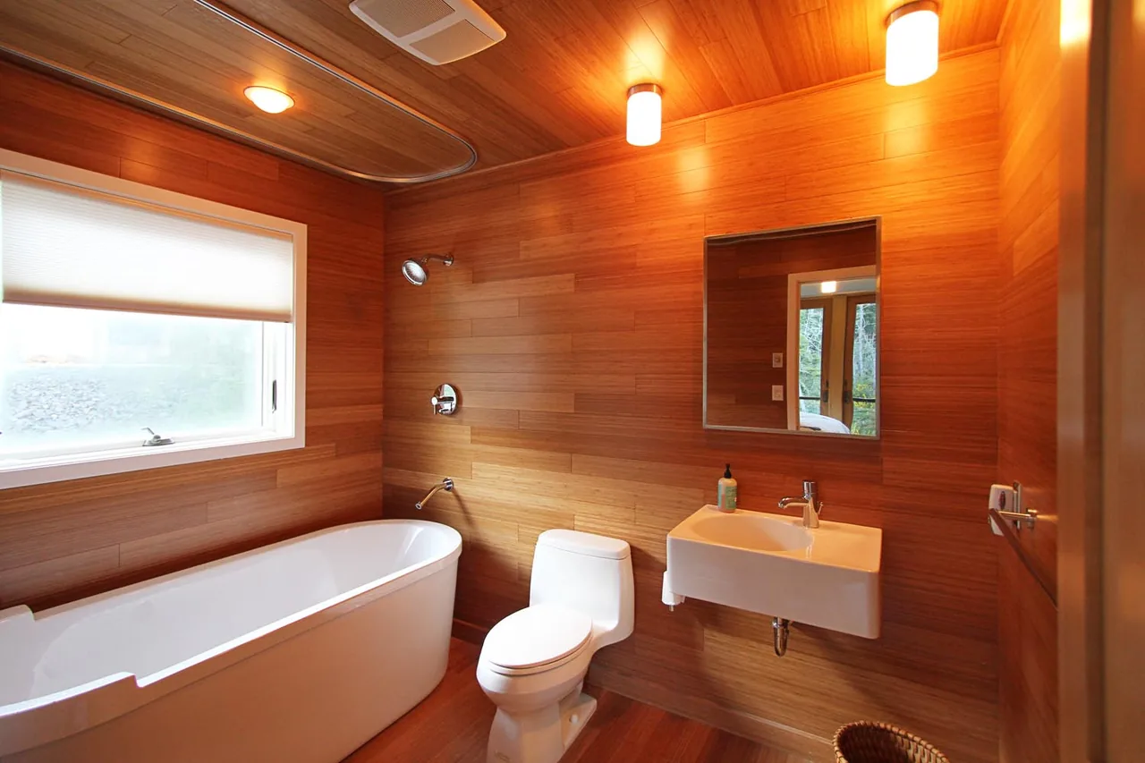 Bathroom features wood paneling and modern white fixtures including freestanding tub and wall-mounted sink.