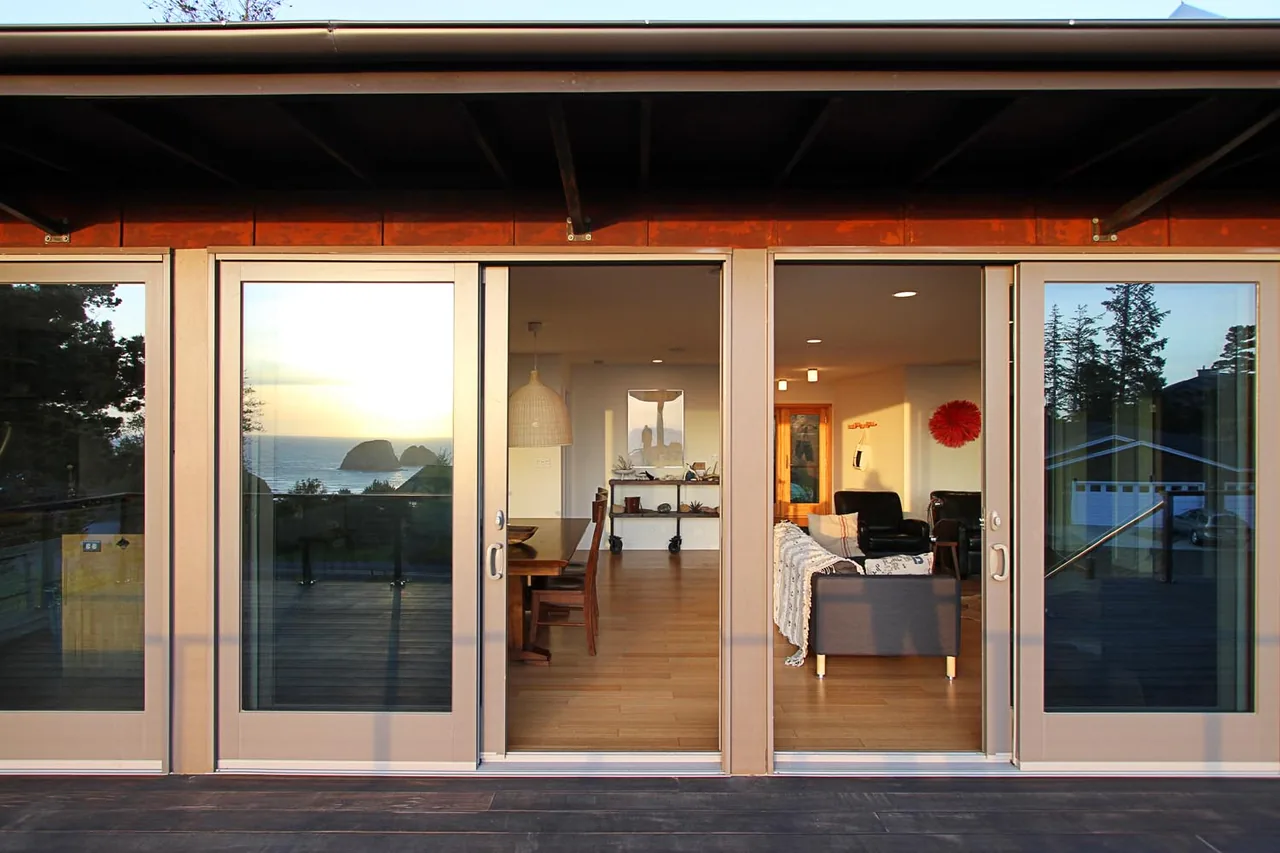 The Oceanside weeHouse features sliding glass doors opening to a deck with ocean views and an open living and dining space inside.