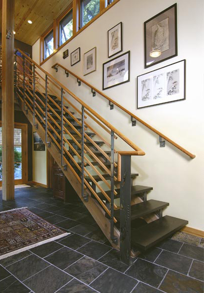 Staircase with wood and blackened steel railing in a home with slate tile floors and wood ceiling.