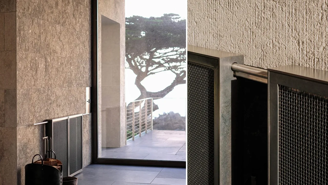 Stone tile wall with metal access panel next to glass door showing tree and waterfront view.