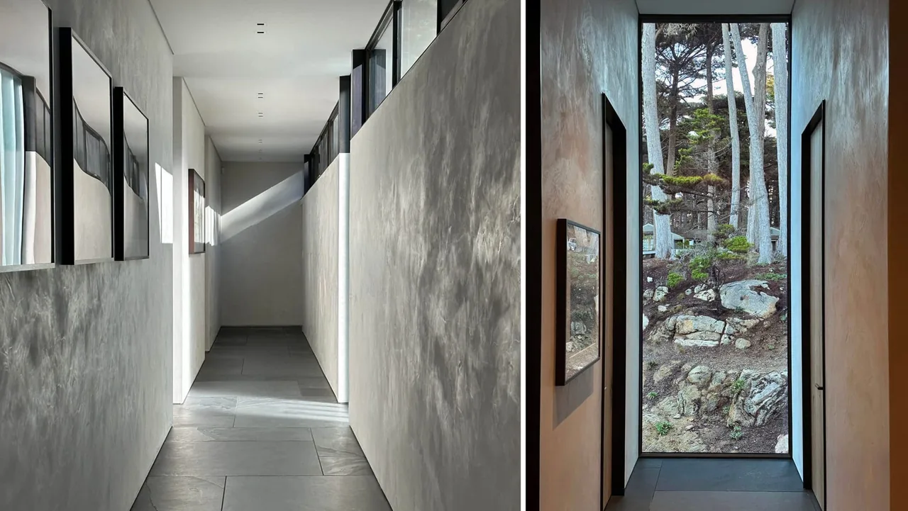 Hallway interior with plaster walls and floor-to-ceiling window framing rocky trees outside at Dogleg Residence by Lundberg Design.