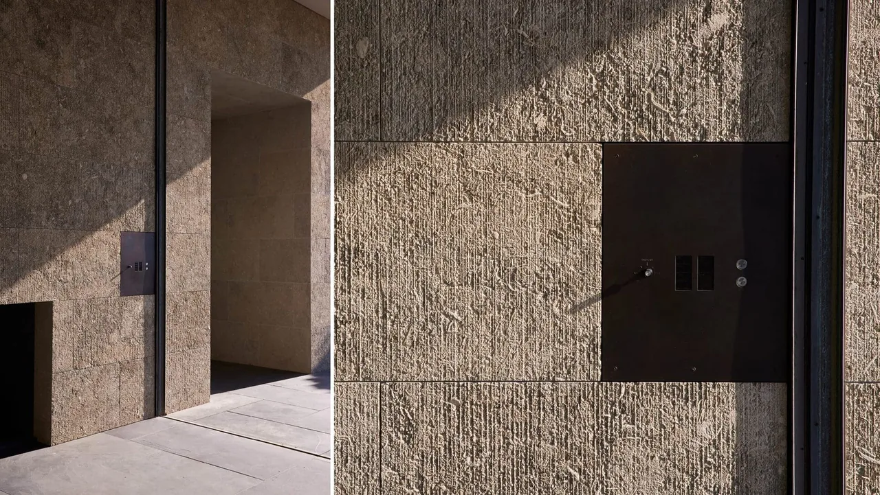 Textured stone exterior wall and metal panel detail at the entrance of Dogleg Residence.