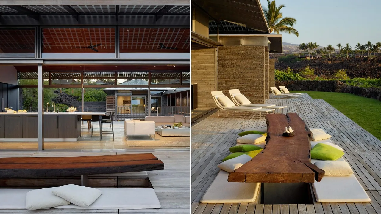 Modern open kitchen and living area with floor-to-ceiling glass doors opening to an outdoor wooden deck with a live edge wood dining table and cushions.