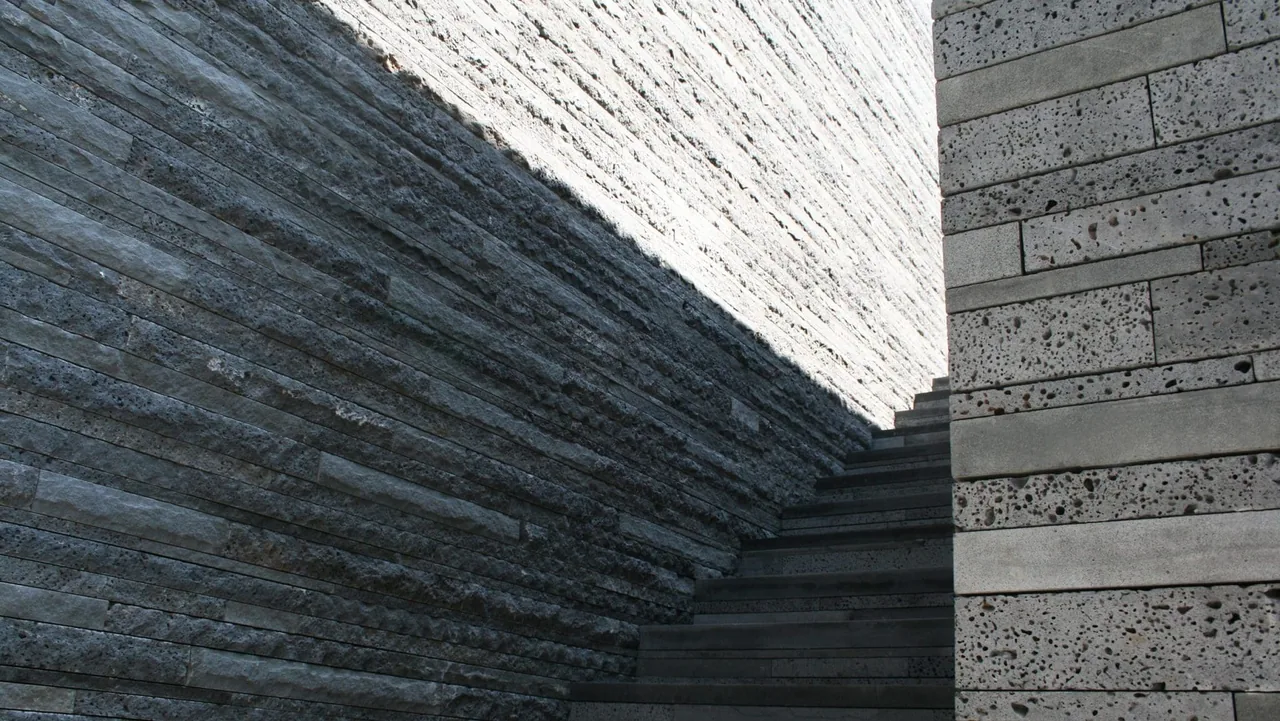 Stone walls create a textured boundary on either side of an outdoor stairway.
