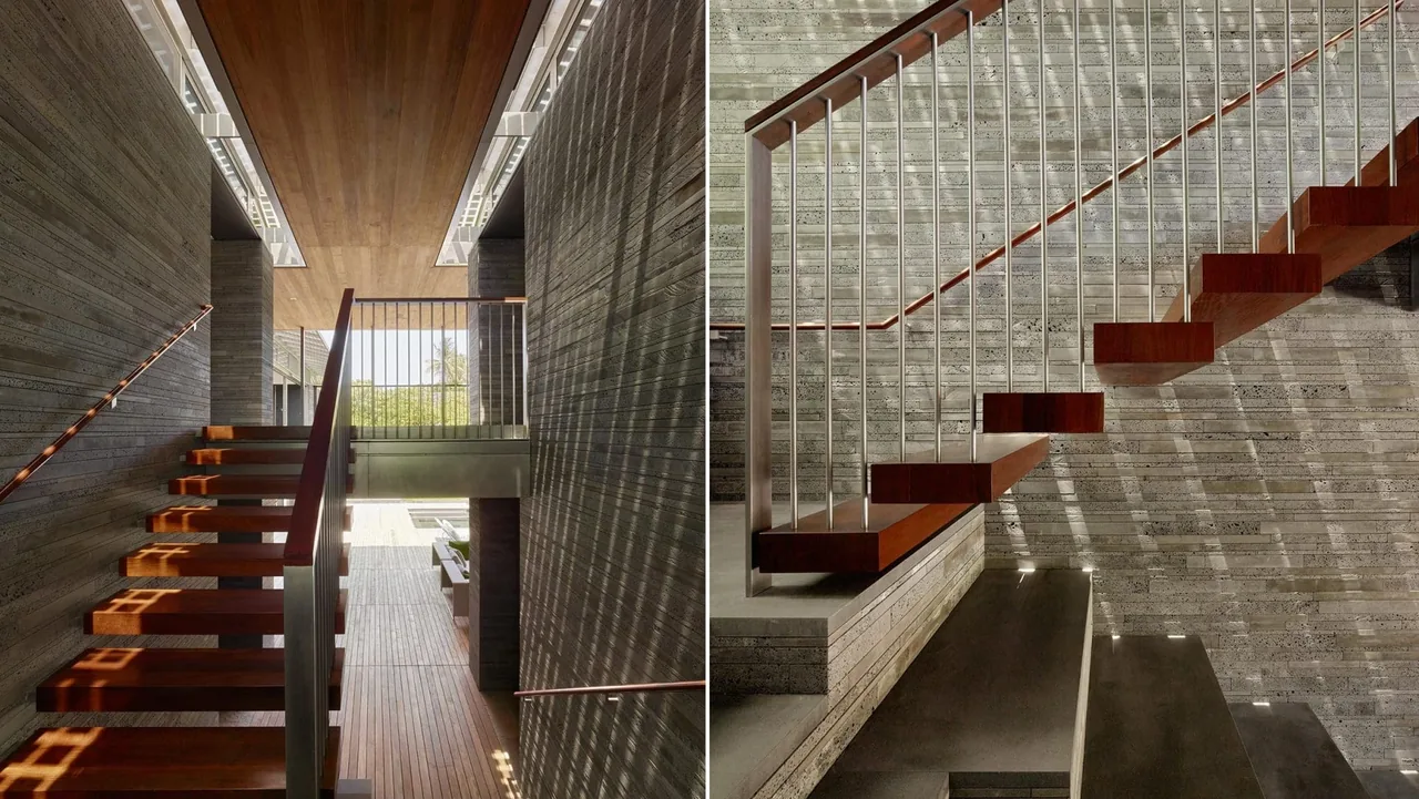 Wooden floating stairs with metal handrails and textured concrete walls in an interior stairwell.