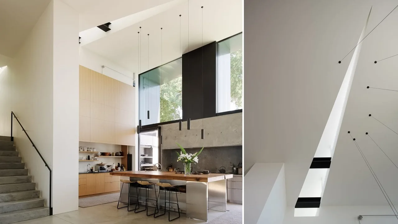Modern kitchen with tall black-framed window, concrete stairs, and wood cabinetry.